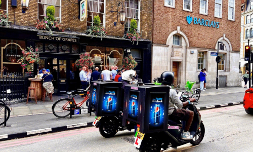 Convoy of Ad|MOTO riders with Ad|BOX screens passing a London pub, Ad|MOTO UK